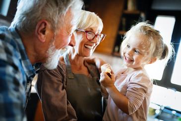grandparents laughing with their granddaughter