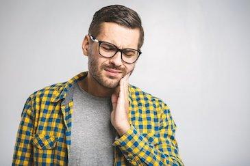 man holding his jaw from pain before a root canal