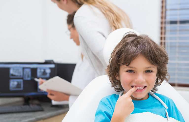 young boy smiling while sitting in the dental chair in appleton