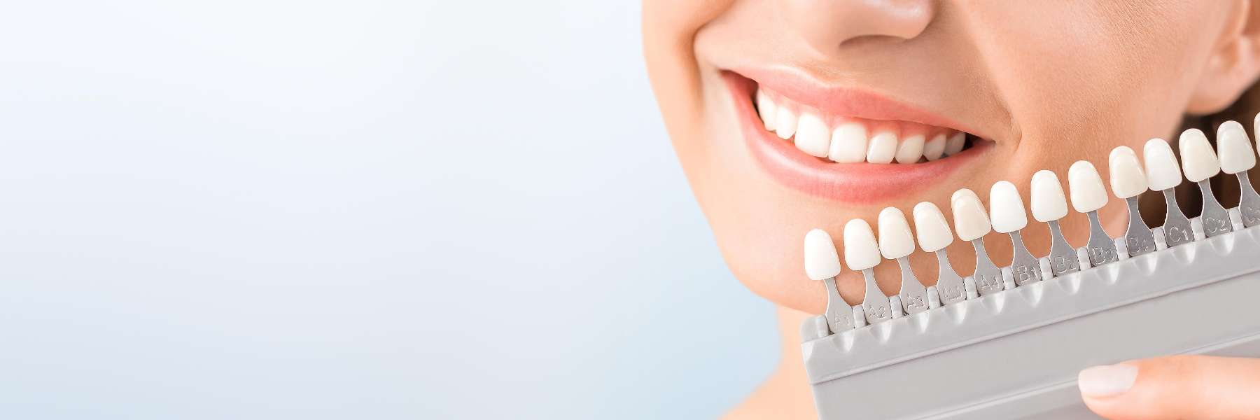 woman holding teeth shades before whitening in appleton